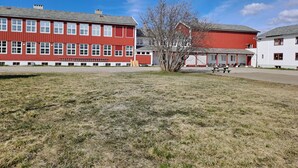 Un bâtiment rouge et blanc avec de nombreuses fenêtres et un arbre devant.