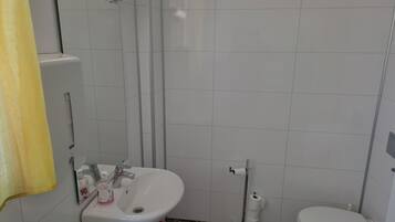 Un baño con lavamanos blanco, inodoro y un cubo de basura rojo.