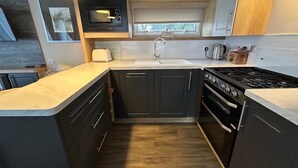 A compact kitchen with a microwave, toaster, sink, and stove. - Rockley Park (Poole)
