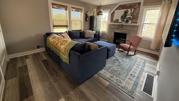 Ein Wohnzimmer mit blauem Sofa, Kamin und einem gemusterten Teppich.