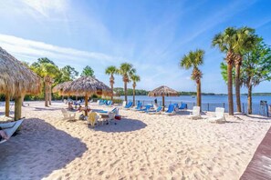 Ein Strand mit Reetsonnenstühlen, Liegen und Palmen.