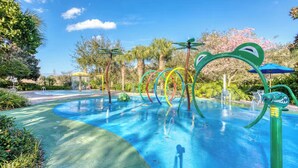 Una piscina con fuentes de agua de colores y palmeras al fondo.