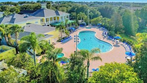 Un resort con una amplia piscina, sillas de descanso y un edificio de fachada amarilla.
