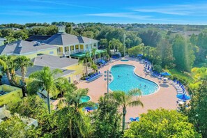 Ein Resort mit einem großen Schwimmbecken, Liegestühlen und einem Gebäude mit einer hellgelben Fassade.