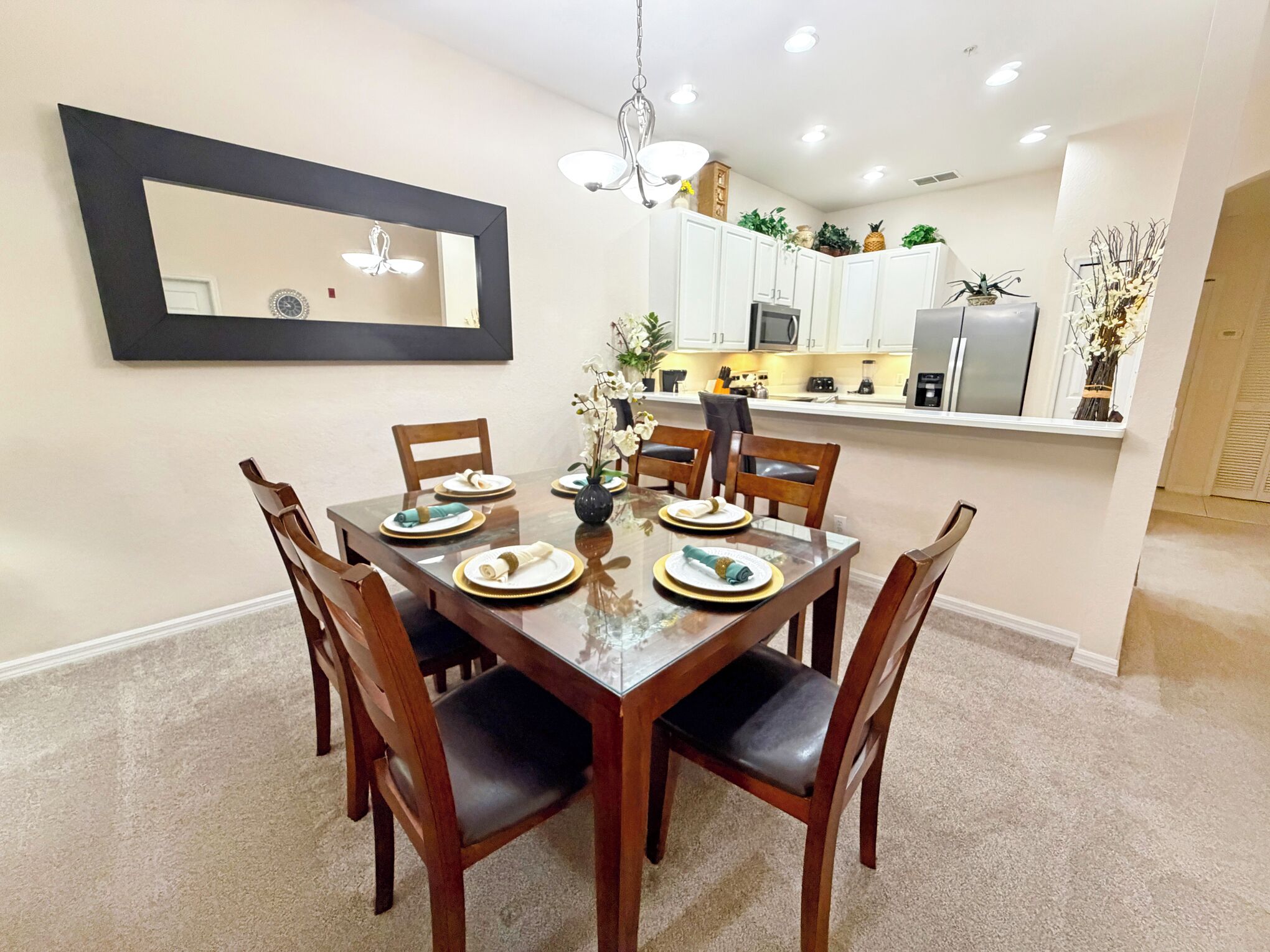 A dining area with a rectangular table, six chairs, and a large mirror on the wall.