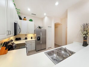 A modern kitchen with white cabinets, stainless steel appliances, and a double sink. - Bright resort condo with private balcony - Bahama Bay (Davenport)