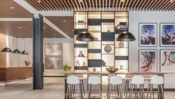 Una cocina moderna con una isla central, iluminación colgante y una barra con taburetes.