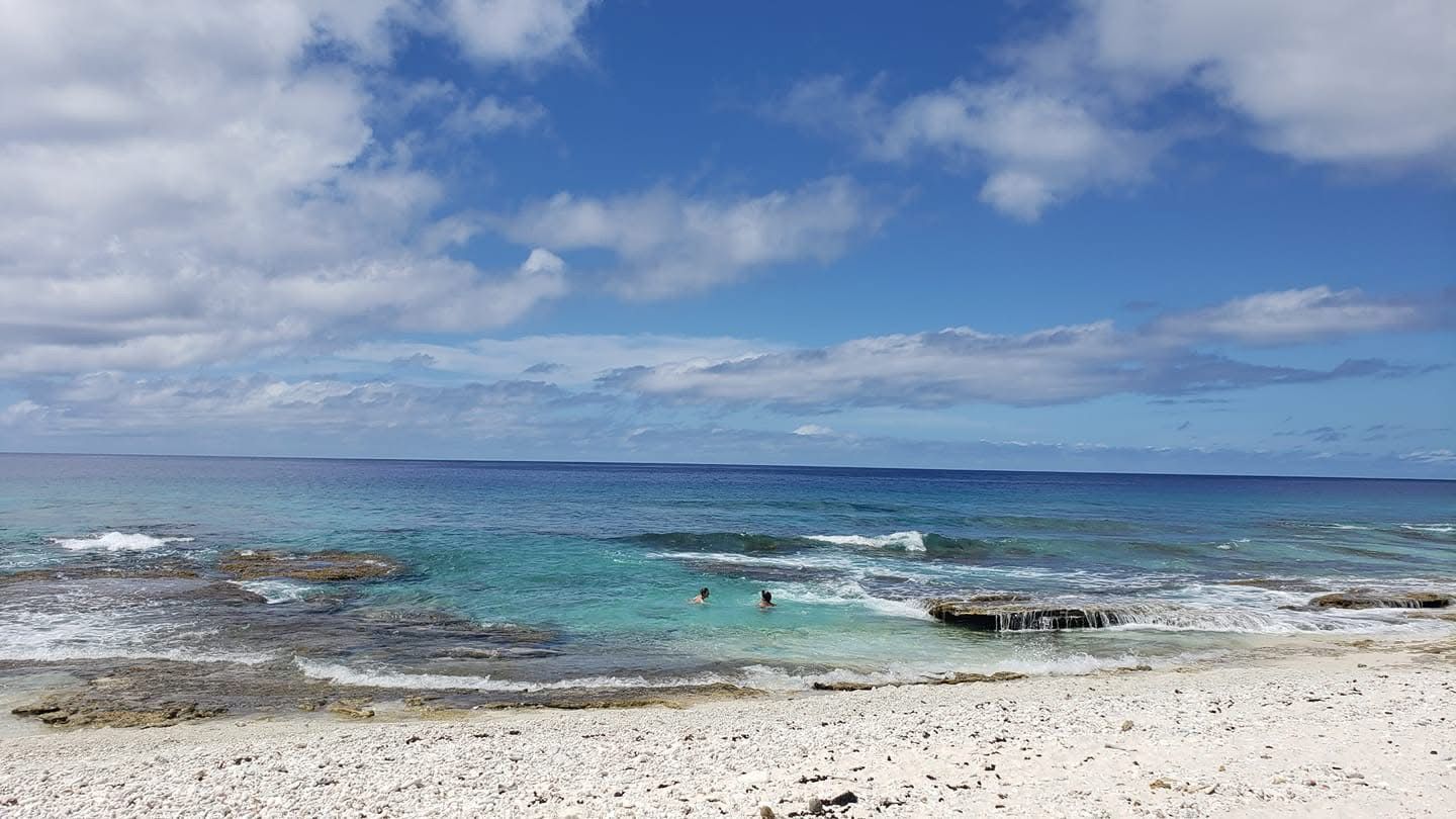 A beach with clear turquoise water, rocky outcrops, and a sandy shore.