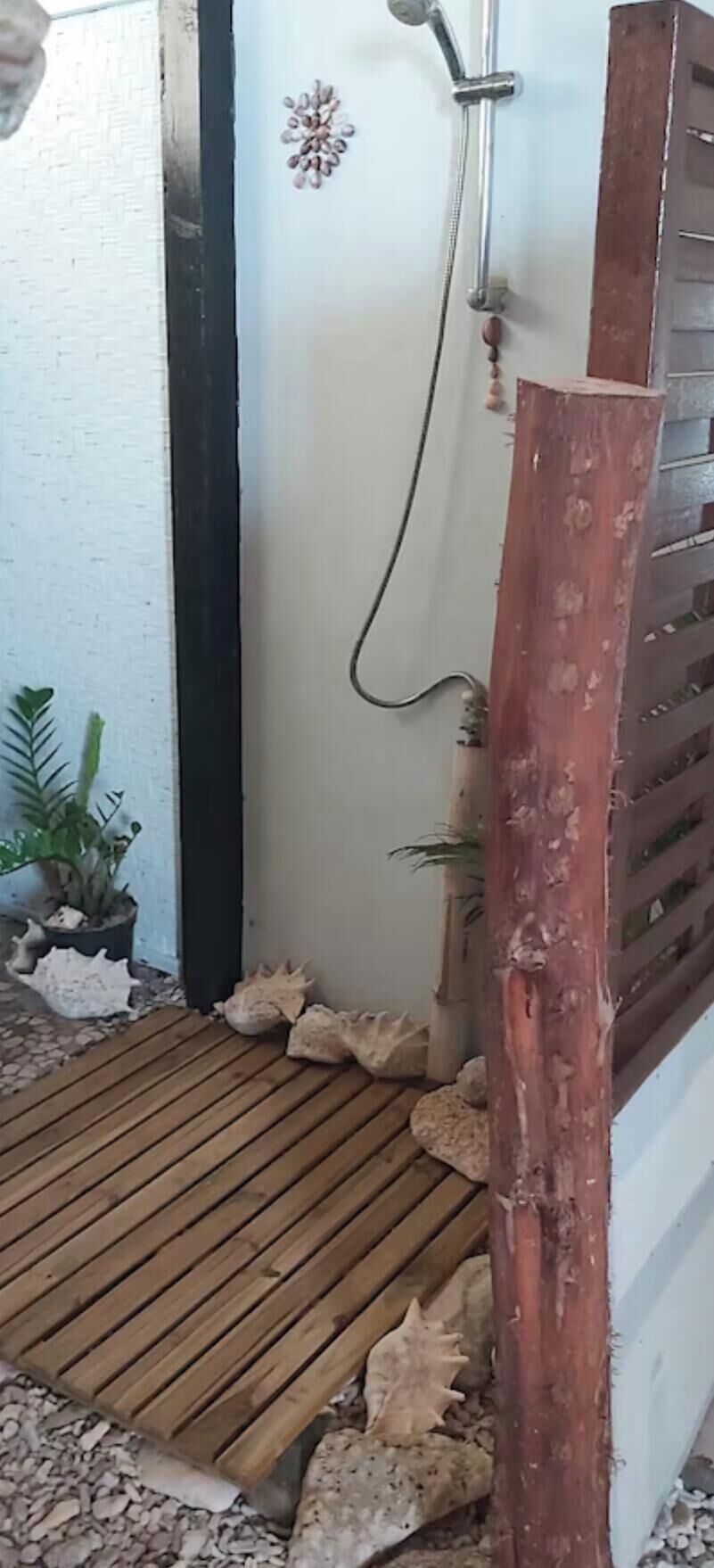 Un espace douche doté d’un sol en bois, d’une pomme de douche et d’un poteau en bois.