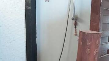 Un espace douche doté d’un sol en bois, d’une pomme de douche et d’un poteau en bois.