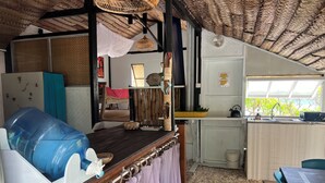 A compact kitchen with a large water dispenser, a sink, and a window with a view. - Fare Miki Miki (Huahine)