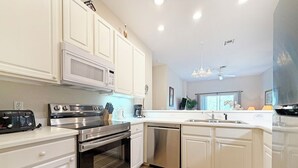 Una cocina moderna con armarios blancos, electrodomésticos de acero inoxidable y una isla grande con un fregadero.
