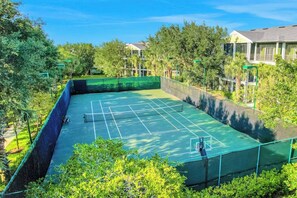 Una cancha de tenis rodeada de árboles y edificios.