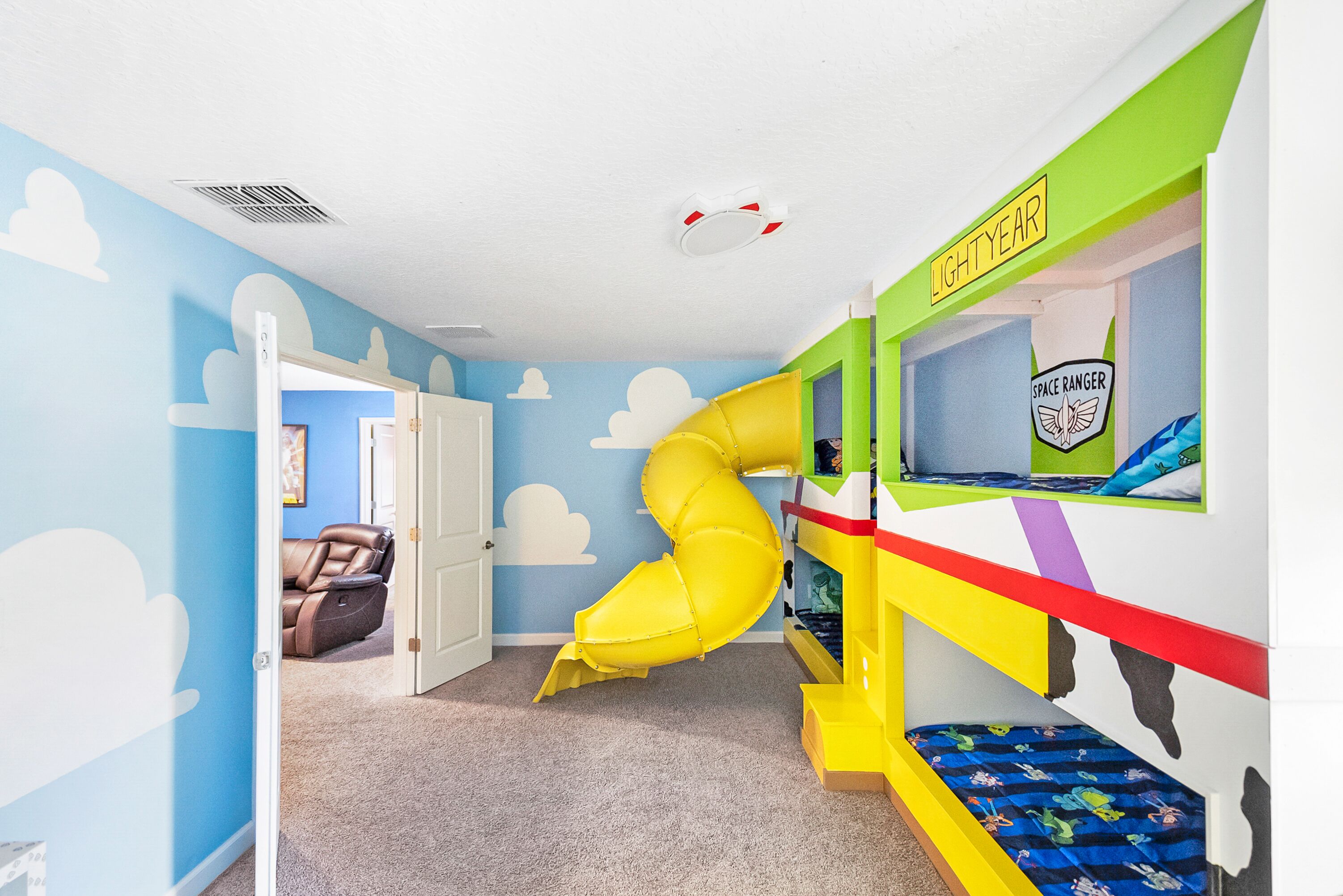A children's playroom with a slide, bunk beds, and a 'Space Ranger' themed wall.