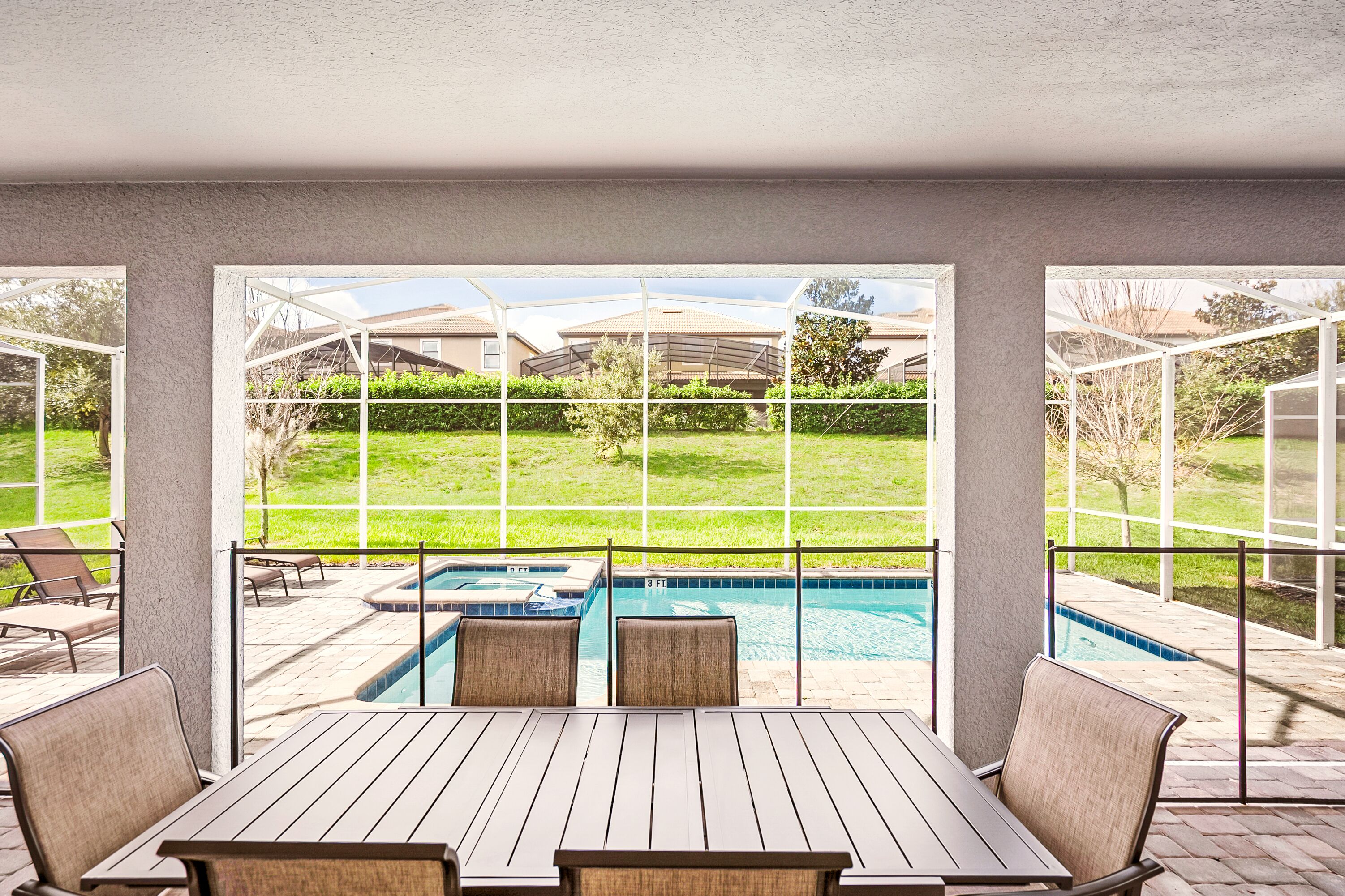 A patio area with a pool, outdoor seating, and a view of a residential neighborhood.