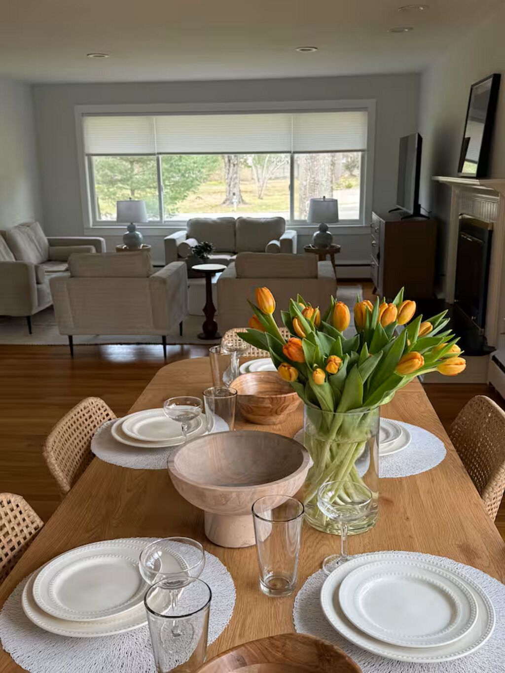 Un coin repas avec une table en bois dressée pour quatre personnes, entourée de chaises en osier.