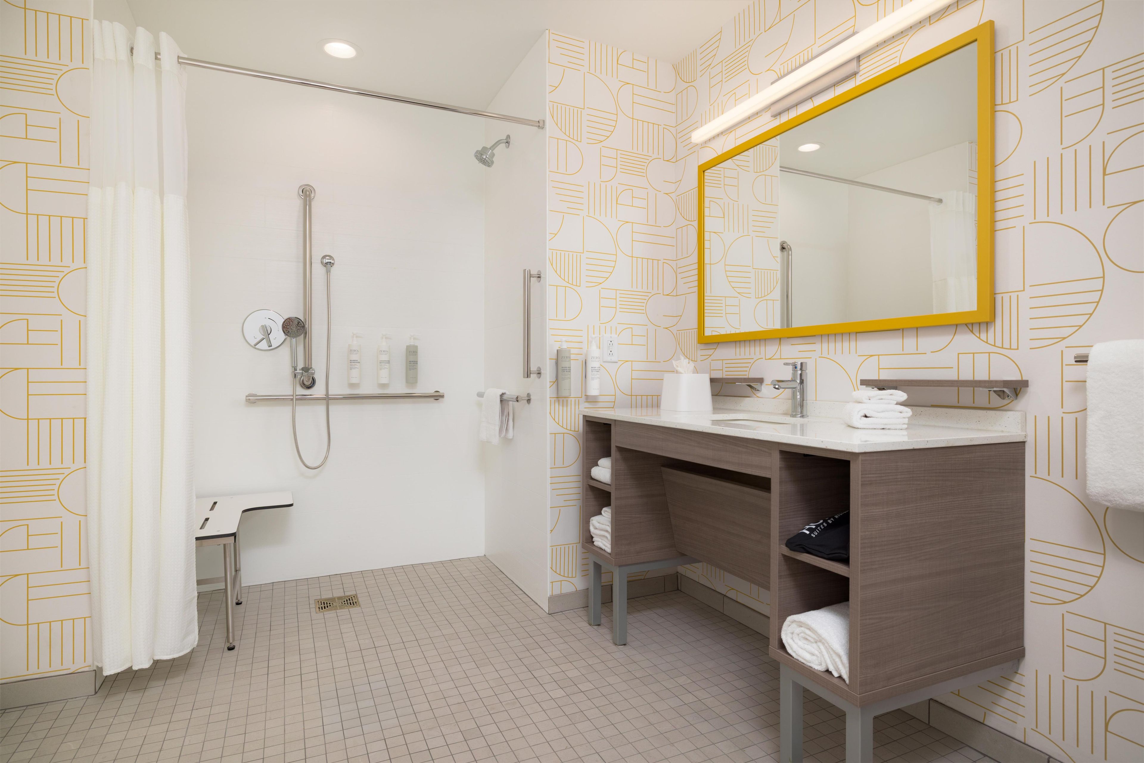 Uma casa de banho moderna com chuveiro, toucador com espelho e porta-toalhas.