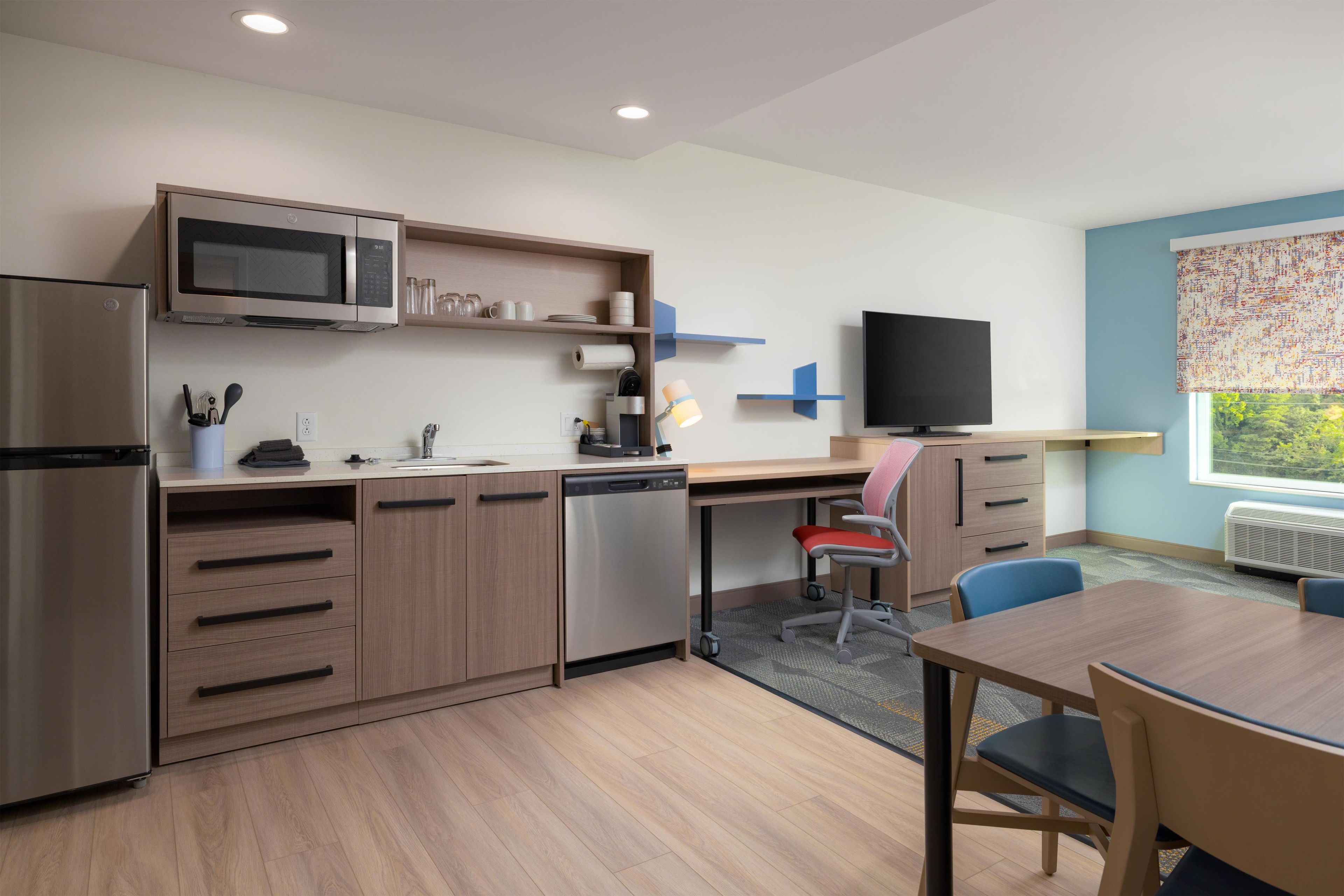 A modern kitchen with a built-in microwave, dishwasher, and a dining area with a table and chairs.