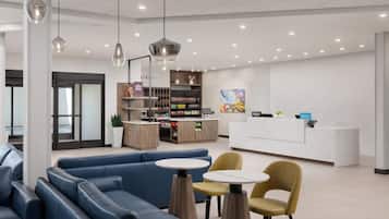 A hotel lobby with seating areas, a reception desk, and a food display.