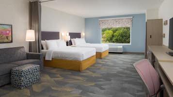 A hotel room with two beds, a sofa, a desk, and a television.
