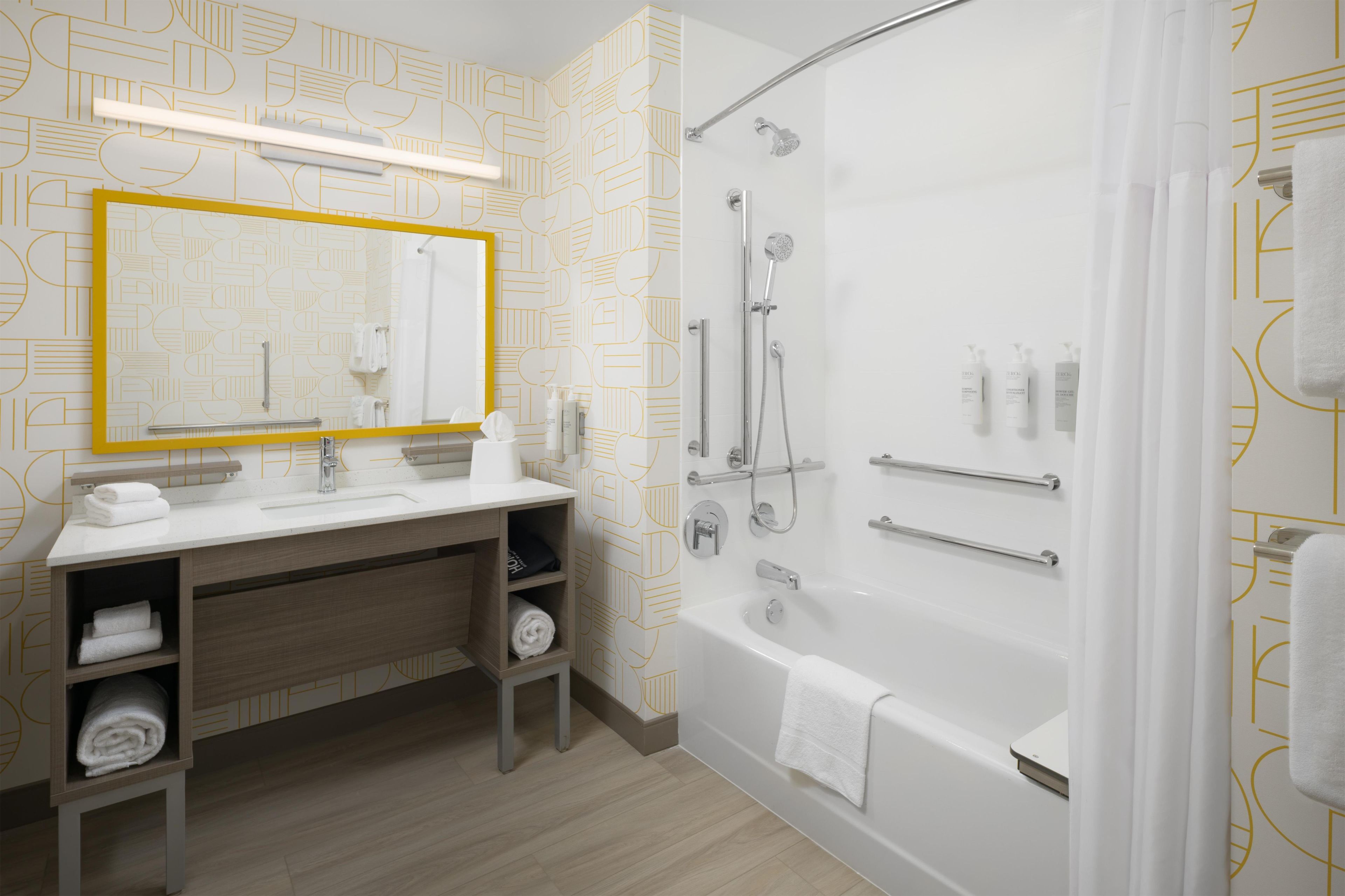 A modern bathroom with a large mirror, dual sinks, a shower, and a bathtub.