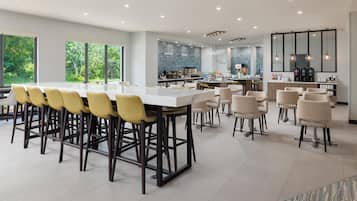 A modern kitchen with a bar area, large windows, and a view of greenery.