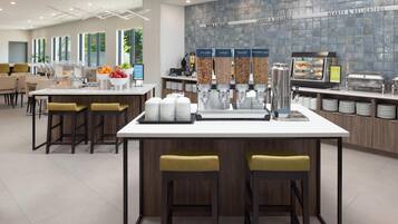 A modern breakfast bar with a coffee machine, cereal dispensers, and a fruit bowl.