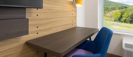 Una habitación moderna con un panel de pared de madera, una mesa, una silla azul y un ventanal con vistas a un paisaje verde.