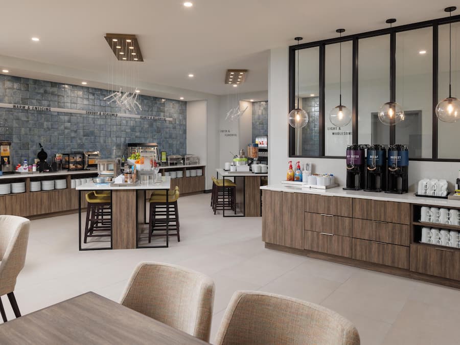 Una cocina moderna con una isla central, taburetes de bar y una barra para desayunos.