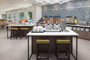A modern breakfast bar with a coffee machine, cereal dispensers, and a fruit bowl.