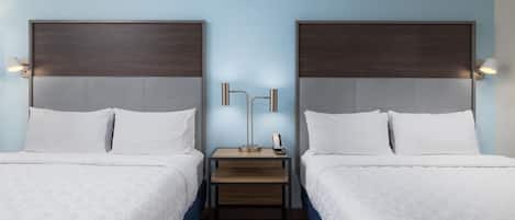 Ein Hotelzimmer mit zwei Betten, einem Nachttisch und einer Lampe dazwischen.