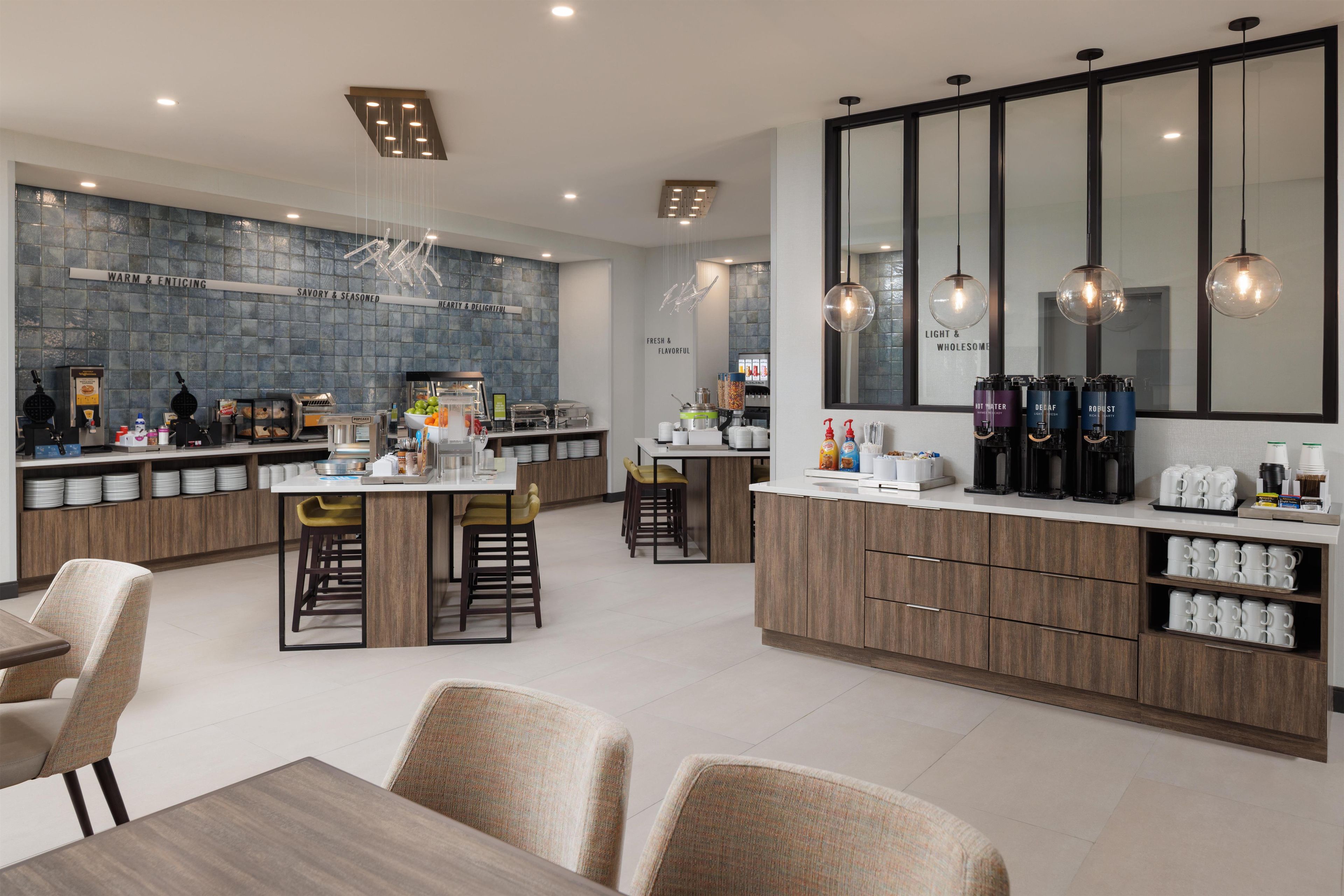 A modern kitchen with a central island, bar stools, and a breakfast bar.