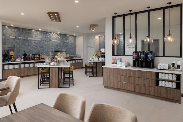 Una cocina moderna con una isla central, taburetes de bar y una barra para desayunos.