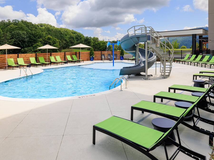 A swimming pool with a water slide, lounge chairs, and a view of the mountains.