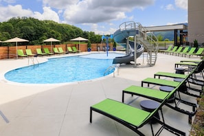 A swimming pool with a water slide, lounge chairs, and a view of the mountains. - Tru By Hilton Chattanooga West Lookout Mountain (Chattanooga)