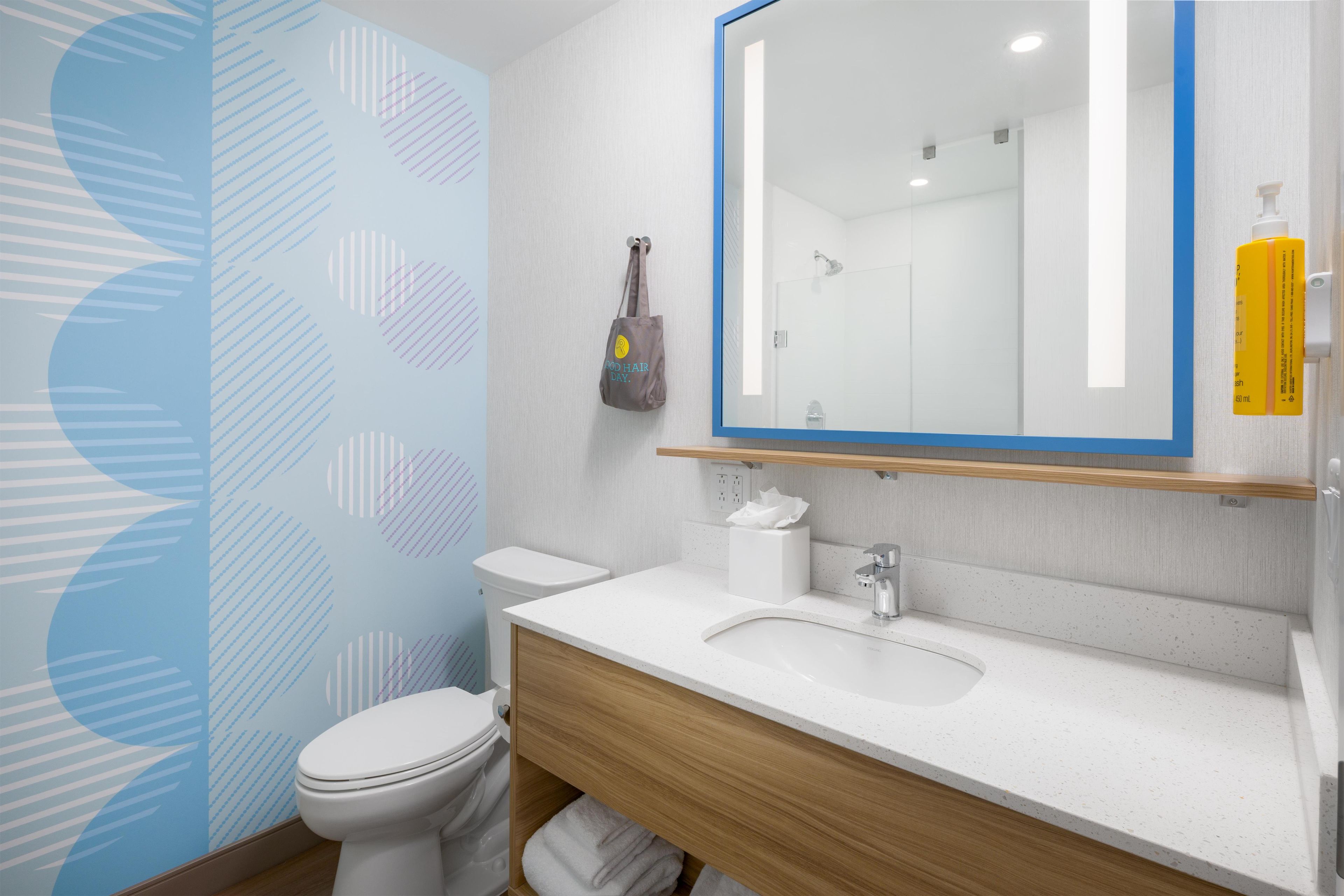 A modern bathroom with a toilet, sink, and mirror.