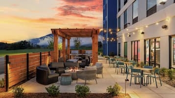 An outdoor patio with seating and a barbecue area, overlooking a mountainous landscape.