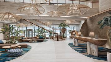 A spacious lobby with a central staircase, multiple seating areas, and a reception desk.