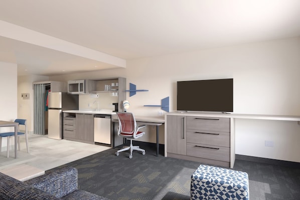 A compact living space with a kitchenette, a dining area, a sofa, and a TV. - Home2 Suites By Hilton Logan (Logan)