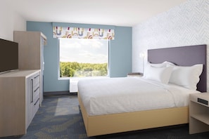 A hotel room with a bed, a TV, a desk, and a window with a view of trees. - Home2 Suites By Hilton Logan (Logan)