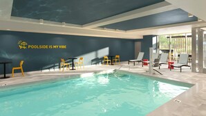 Piscina interna com parede azul e logotipo com a frase 'POOLSIDE IS MY VIBE'.
