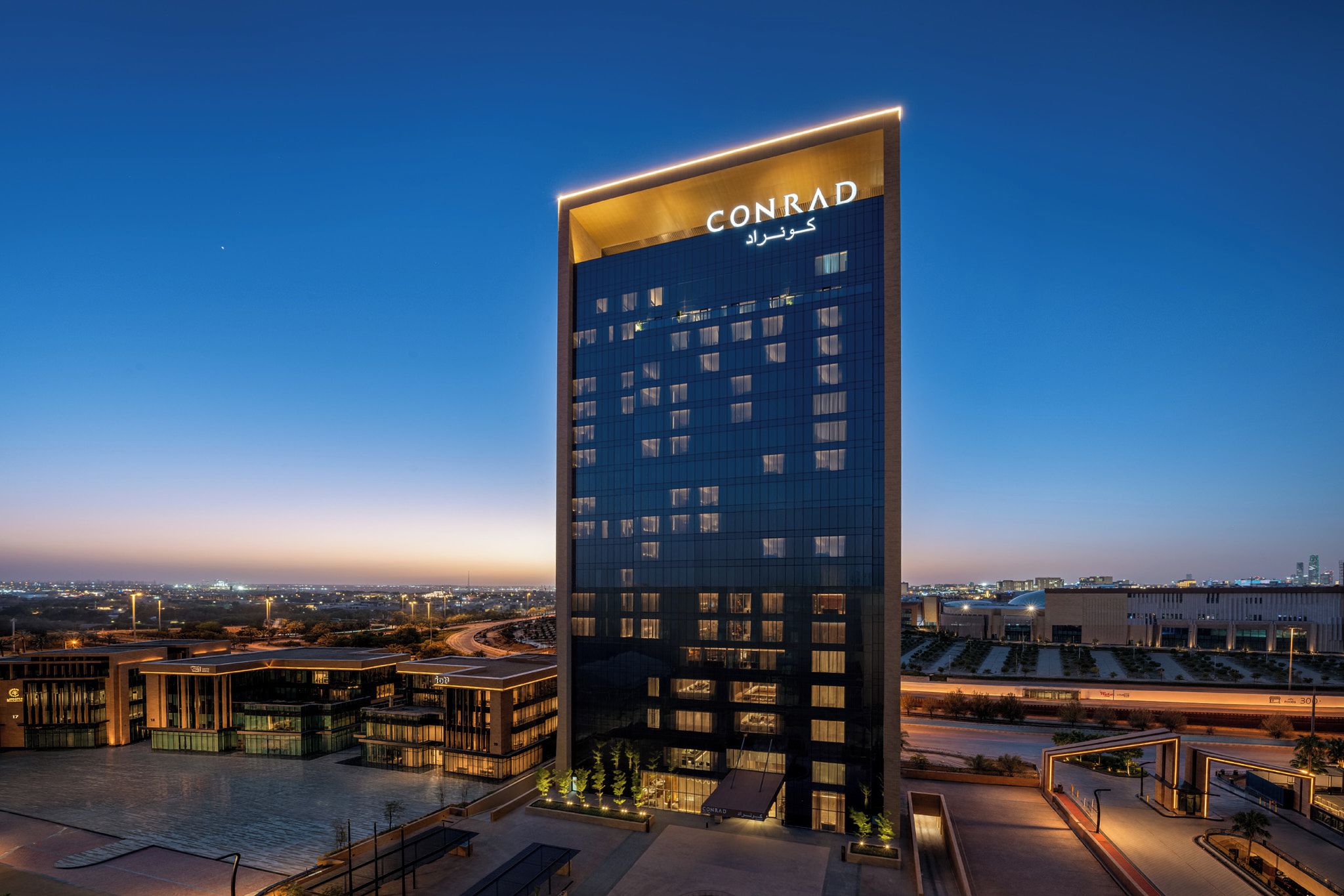 Un immeuble de grande hauteur sur lequel le nom « CONRAD » est clairement affiché en haut.