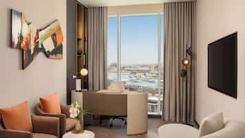 A modern hotel room with a large window, a desk, a sofa, and a TV.