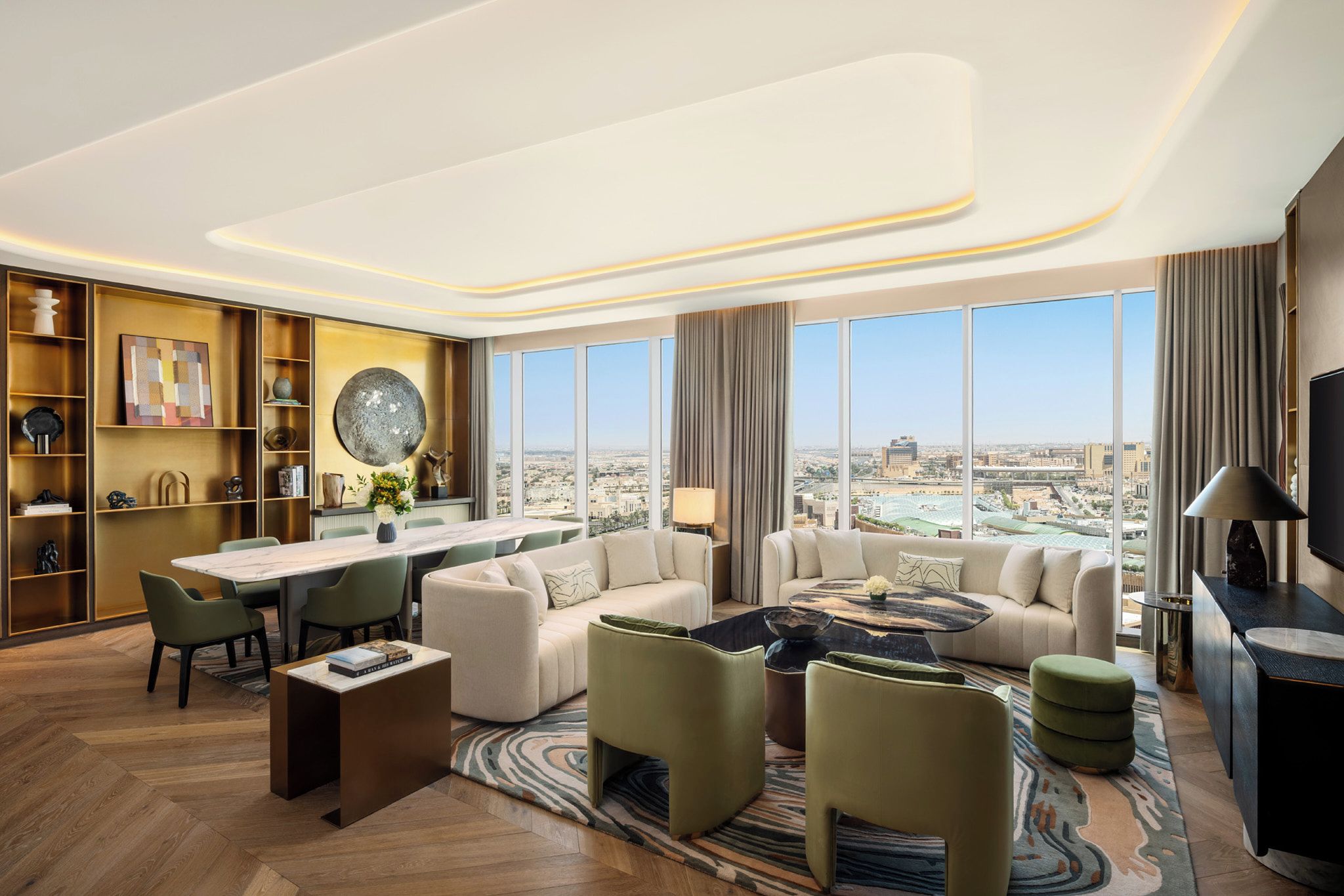 Une chambre d’hôtel moderne dotée d’un coin repas, d’un ensemble de canapés, d’une table basse et offrant une vue sur la ville.