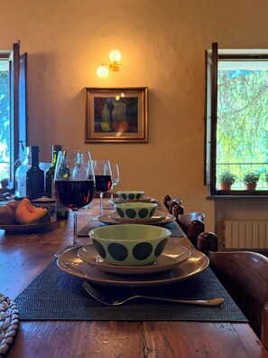 Un tavolo da pranzo con una serie di ciotole a pois verdi, bicchieri da vino e bottiglie.