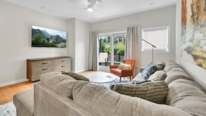Ein Wohnzimmer mit einer Couch, einem Couchtisch, einem Fernseher und einem Sessel.