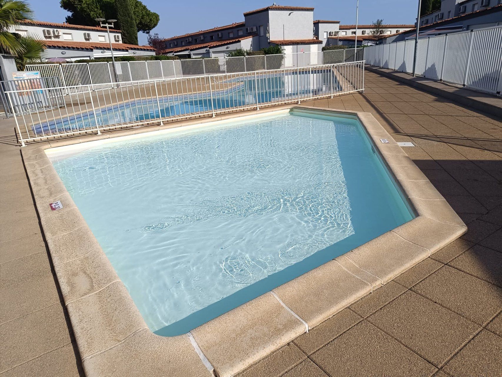 A rectangular swimming pool with a tiled deck surrounding it.