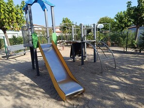 A playground with a slide, climbing structures, and a bench.