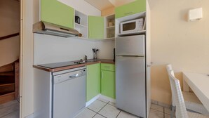 A compact kitchen with a dishwasher, microwave, and a small dining area with a chair. - Les jardins de Neptune, pool and relaxation (Saint-Cyprien)