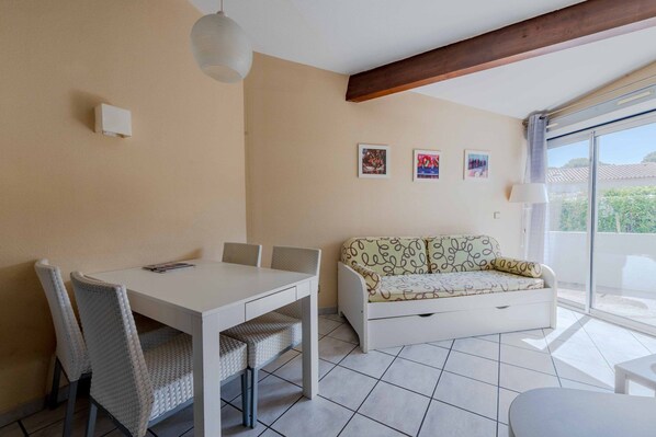 A room with a dining table, chairs, a sofa, and a window with a view.